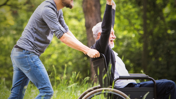 Image of a man in a wheelchair with his hands in the air and smiling