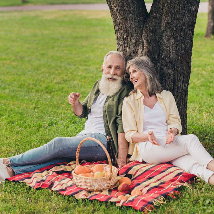 Two elderly people sitting in a park having a picnic