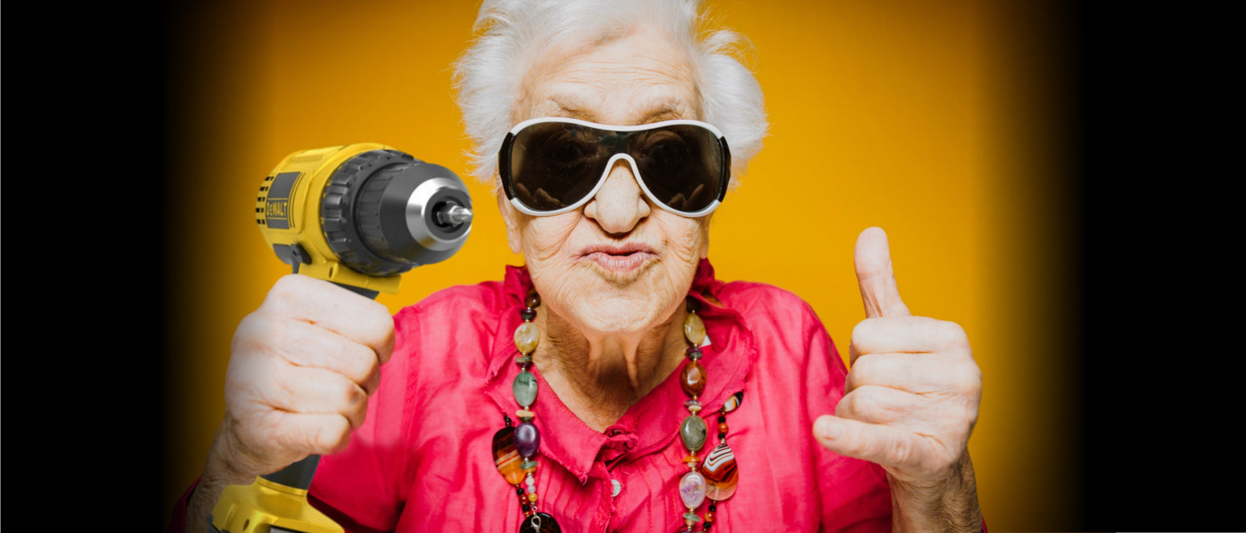 Elderly woman holding a power drill and wearing sunglasses