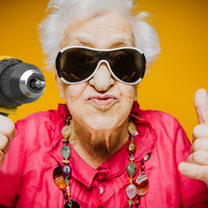 Elderly woman holding a power drill and wearing sunglasses