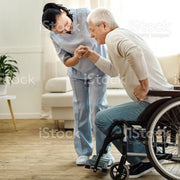 A nurse helping a man out of his wheelchair in a lounge